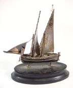 A Continental silver model of a fishing boat: set full sails, mounted on an oval ebony socle,