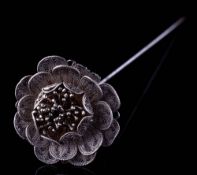 An early 20th century white metal filigree hat pin in the form of a flower,: 26cm long.