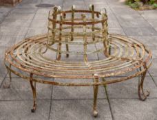 A wrought iron circular tree guard seat:, of slatted design on shaped scroll legs,