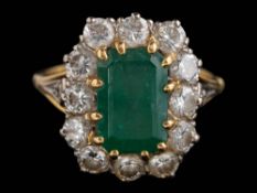 An emerald and diamond cushion-shaped cluster ring: with central rectangular emerald 10.