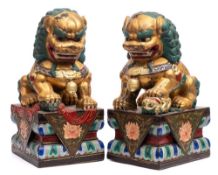 A pair of Chinese carved wood and polychrome decorated lion dogs: with fixed staring eyes and