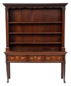 An 18th Century oak dresser:, the shelved superstructure with a moulded dentil cornice,