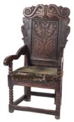 A 17th Century carved oak open armchair:, the back with shaped top rail decorated with twin snakes,