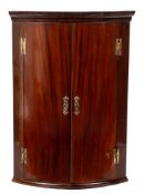 A mid 18th Century mahogany bow-fronted hanging corner cupboard: with a moulded cornice,
