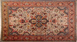 A Tabriz carpet:, the beige field with a central indigo pole medallion with palmette designs,