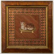 A 19th century petit point woolwork picture of a cat: seated on a tasseled cushion,