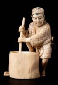 A Japanese carved ivory okimono: of a peasant pounding grain,