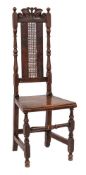 A Carolean carved beechwood dining chair: the high cane panel back with foliate scroll cresting and
