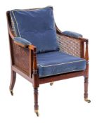 A Regency mahogany library Bergere armchair:, with a reeded frame, having a curved cane panel back,