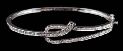 A modern diamond mounted hinged bangle: with small brilliant and baguette-cut diamonds estimated to