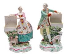 A pair of Derby figures of a gallant and lady: each with an open basket and a seated dog at their