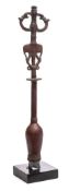 A bronze staff head : surmounted by an idol, on a knopped stem and square plinth base,