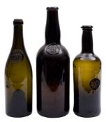 A group of three green glass sealed wine bottles: including a George III cylindrical bottle with