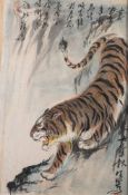 A Chinese painting of a tiger, signed Xiao-bai: the animal crouching on a steep bank,