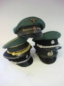 A collection of five reproduction German military peaked caps and a small group of cloth badges.