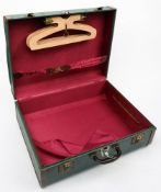 An American travelling trunk: green with brown border, red silk fitted interior with hangers.