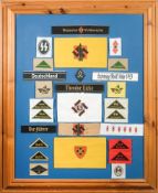 A framed collection of German armbands and shoulder badges.