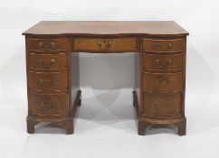 Modern serpentine fronted mahogany desk with nine assorted drawers, bracket feet