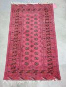 Red Bokhara-style rug with central rectangular field with octagonal patterns surrounded by three