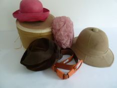 A Pith helmet, cardboard hat box , three hats and an orange leather belt.