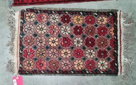 Small Eastern rug, salmon ground, flowerhead motif, 76cm x 41cm