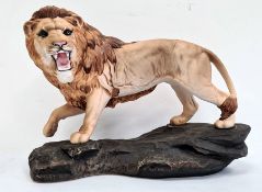 Beswick tinted bisque porcelain model lion on rockwork, 30cm wide