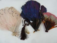 A purple feather and tortoiseshell fan, 19cm, a tortoiseshell and pink/grey feather fan, a wooden