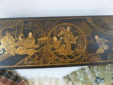 An oriental lacquered glove box, black with gilt decoration to lid, depicting seated figures in an