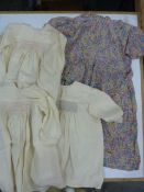 Three cream silk smocked dresses, a rayon floral patterned dress with tie  belt, frill detail to the