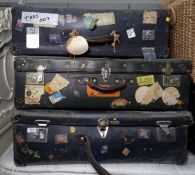 Three large travelling suitcases bearing many travel labels, including British Airport, The