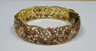 Indian(?) gold ?, ruby and seedpearl bangle, pierced scroll and floral decoration, unmarked, 42.5g