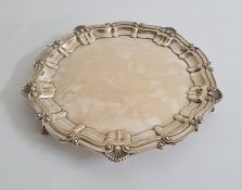 Early 20th century silver salver, circular with scroll and shell decoration, on three claw and