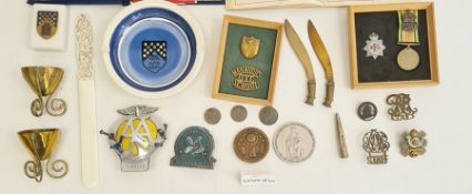 Collection of military badges, a military-style pocket compass, brass trench art, an AA car