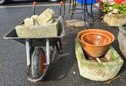 Gardeners wheelbarrow containing D-end stone trough and four stone cornice pieces, another D-end