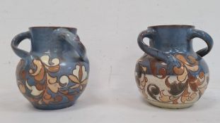Pair H Brannam Barum glazed terracotta three-handled vases, each foliate decorated on a blue ground,