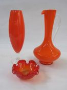 Orange glass jug with clear glass handle, an orange glass vase of elliptical shape with clear