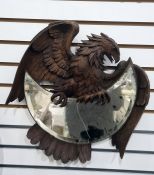 Early 20th century Black Forest mirror modelled as a carved eagle holding a crescent-shaped bevelled