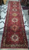 Persian style wool runner, red ground with lozenge and square medallions, floral borders, with one