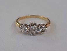 Gold graduated three stone diamond ring, marked 18ct, the central brilliant cut diamond measuring