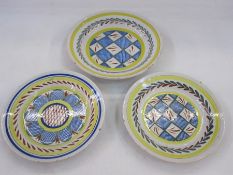 Three Delft plates, two with cross-hatch decoration in blue, red and green, with laurel to rim and