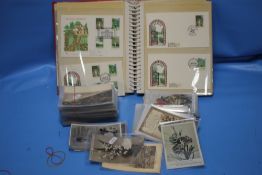 AN ALBUM OF FIRST DAY COVERS TOGETHER WITH A SMALL COLLECTION OF ASSORTED POSTCARDS