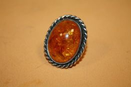 A LARGE SILVER MOUNTED AMBER RING