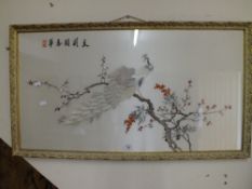 A GILT FRAMED AND GLAZED ORIENTAL NEEDLEWORK ON SILK DEPICTING A PEACOCK ON A BRANCH OVERALL SIZE