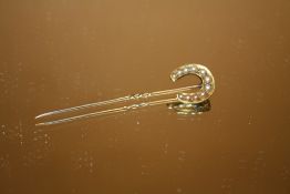 AN UNMARKED YELLOW METAL HORSESHOE SHAPED STICK PIN SET WITH SEED PEARLS