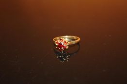 A HALLMARKED 9 CARAT GOLD FLORAL SET GARNET DRESS RING - SIZE L - WEIGHT 1.4 GRAMS APPROX