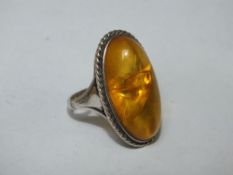 A LARGE SILVER MOUNTED AMBER RING