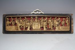 AN ORIENTAL CARVED AND GILT WOOD RECTANGULAR PANEL, modelled as figures carved in relief around a