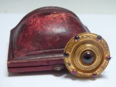 A CIRCULAR MOURNING BROOCH, in a Celtic shield style with seven cabochon ruby type stones,