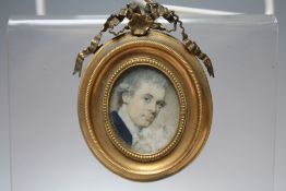 A 19TH CENTURY OVAL PORTRAIT MINIATURE, depicting a Georgian gentleman in a blue coat, set in a