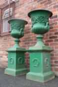 A LARGE PAIR OF ANTIQUE CAST IRON CAMPANA SHAPED URNS ON STANDS, each urn with twin handles,